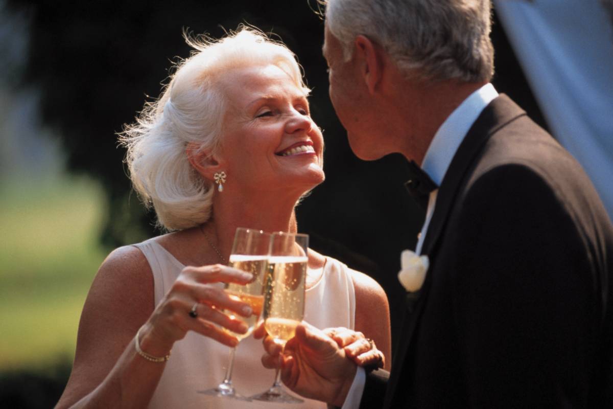 Un couple souriant trinque au champagne pour célébrer ses 25 ans de mariage, symbole des noces d’argent et d’un amour durable.